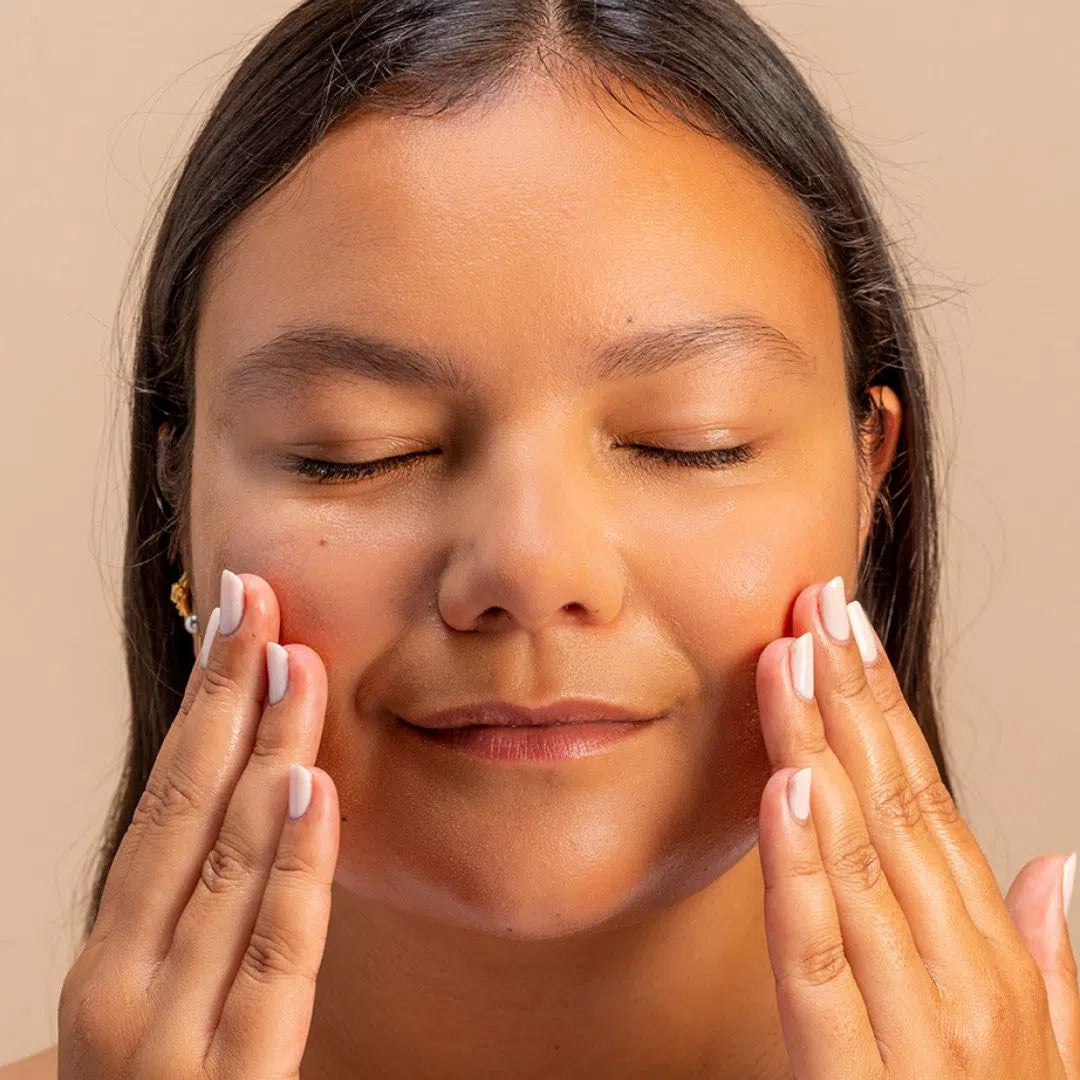 Visage d'une femme qui s'applique avec les mains l'huile démaquillante sans coton aux paquerettes et aux oeillettes de Oden