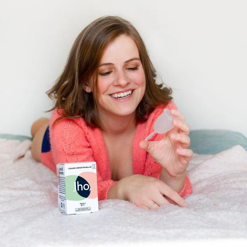Femme qui tient une coupe menstruelle avec tige en silicone médical taille deux pour flux moyende Jho avec sa boîte