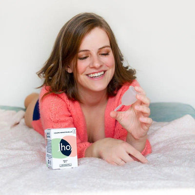 Femme qui tient une coupe menstruelle avec tige en silicone médical taille deux pour flux moyende Jho avec sa boîte