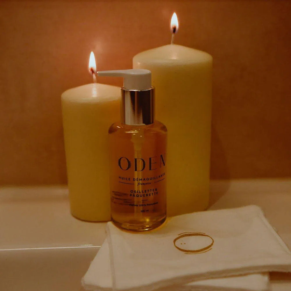 Huile démaquillante sans coton aux paquerettes et aux oeillettes de Oden  avec des bougies sur un lavabo
