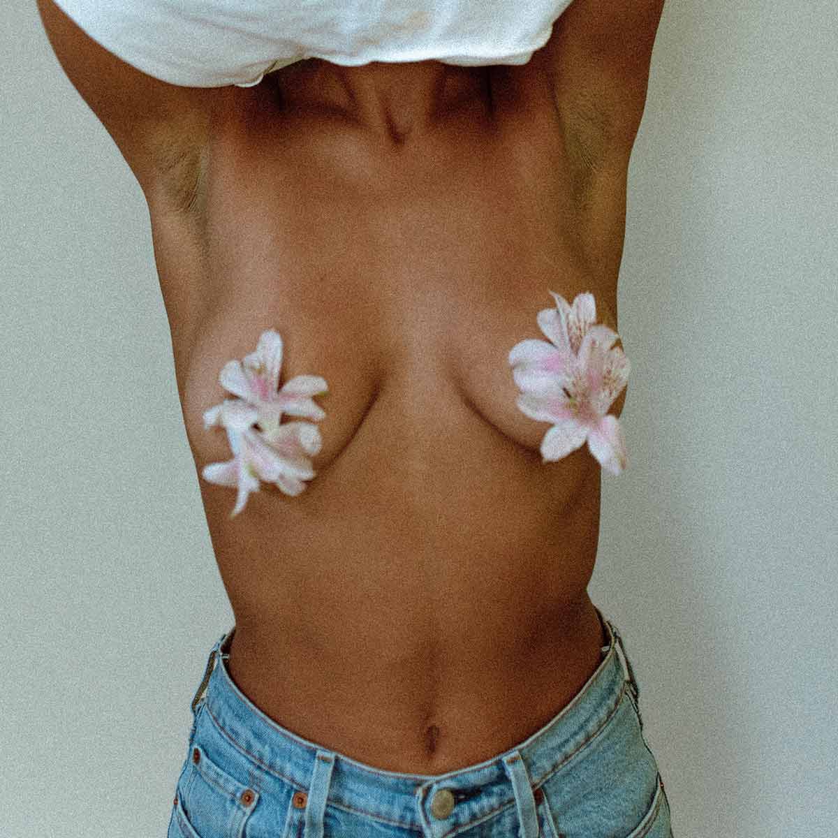 Femme torse nu avec des fleurs au bout des seins